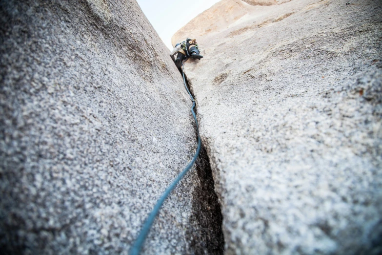 a pair of climbing shoes hanging from the side of a large boulder