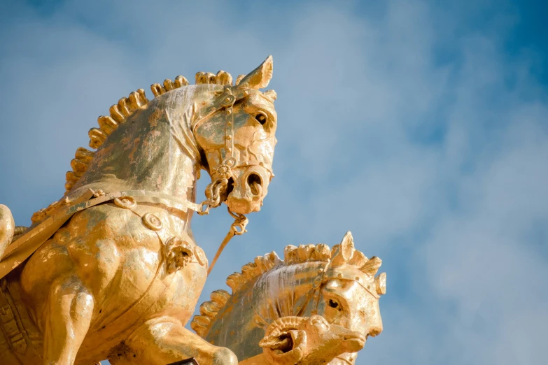 there are gold horses and a golden statue on a pillar