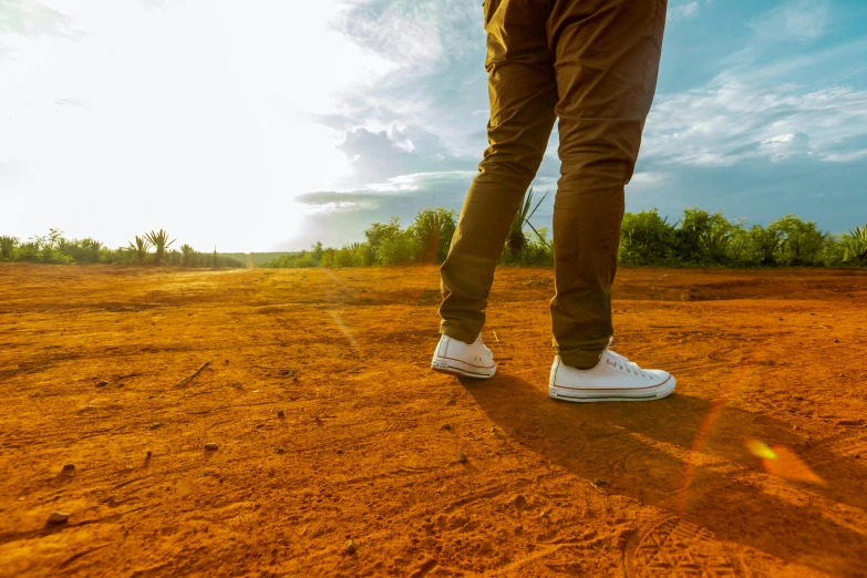 a pair of shoes stands on the dirt in the sun