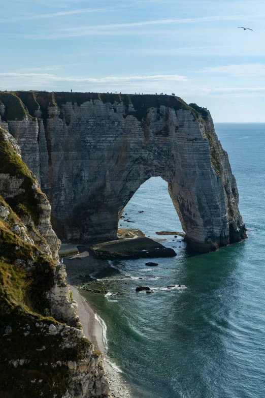 an arch shaped stone bridge spanning the width of a body of water