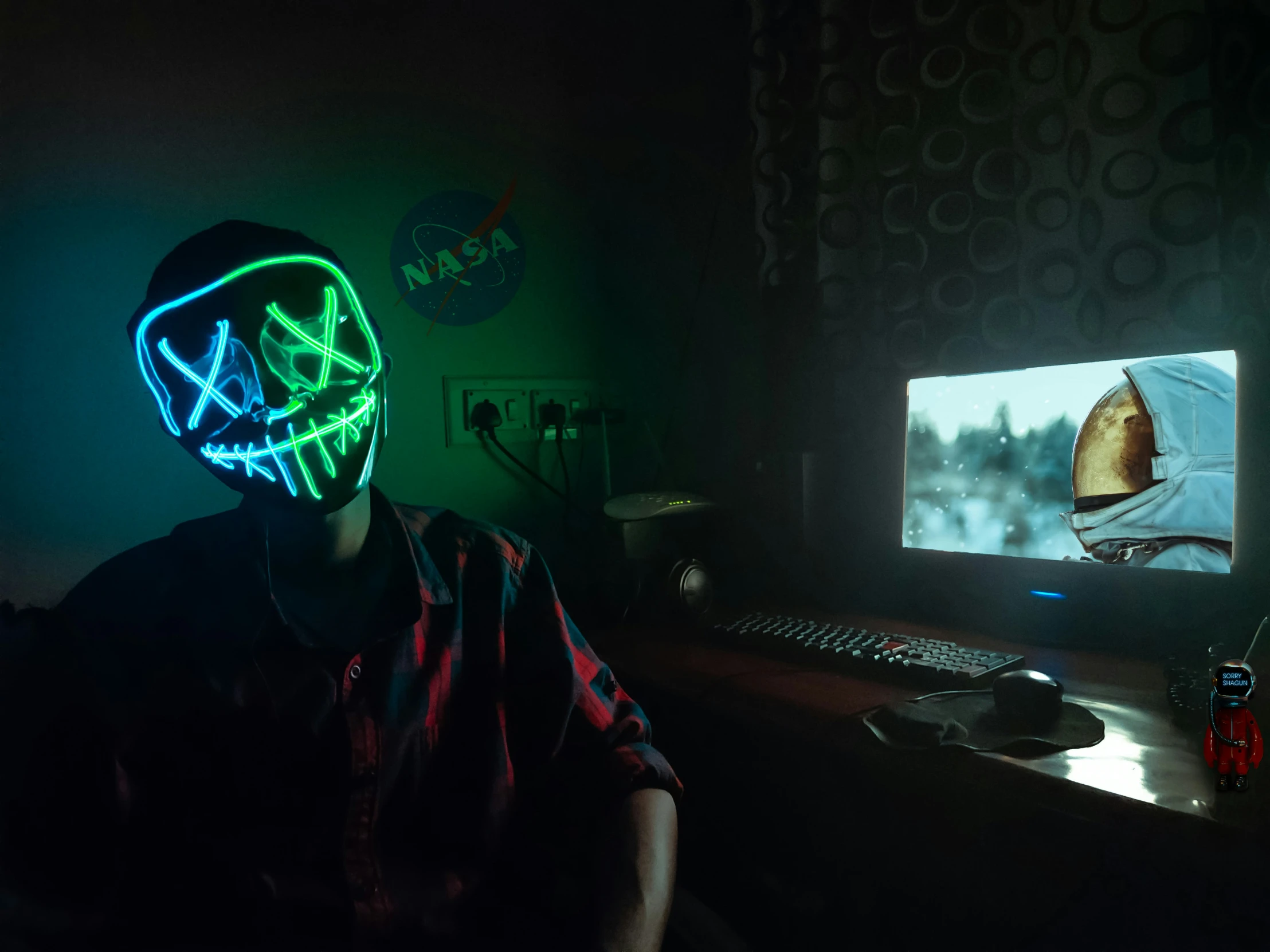 person wearing a neon neon mask while sitting in front of a computer