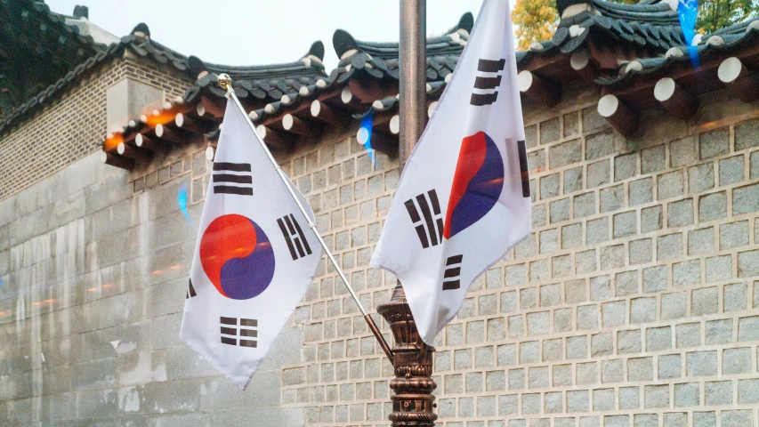 two flags sticking out of a pole near a wall