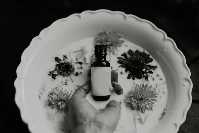 black and white pograph of a hand holding a small bottle