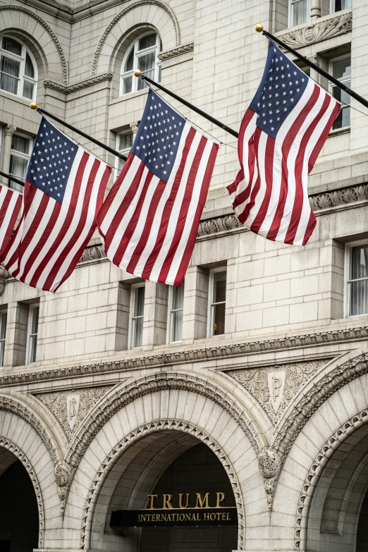 several flags hanging outside a building with stone archways