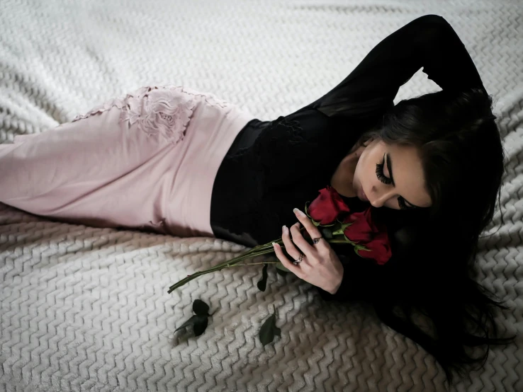 a young woman laying on a bed holding flowers