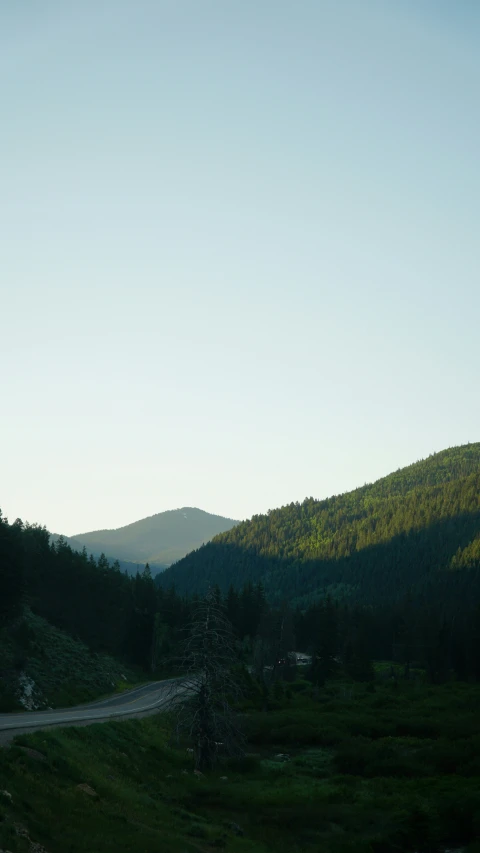 a dirt road running through a green mountain