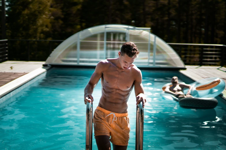 a man in swim trunks standing on skis in an above ground swimming pool