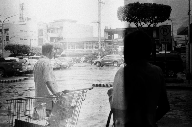 people standing in front of a store window with umbrellas on a rainy day