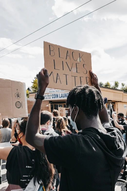 a man holds up a sign that reads black lives matter