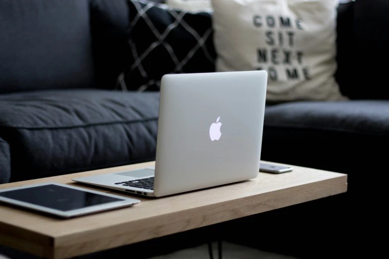 the table is made from wood with an apple laptop and phone