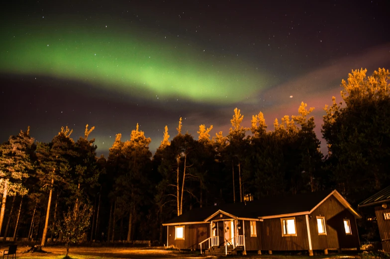 a couple of house are seen with the aurora light in the distance