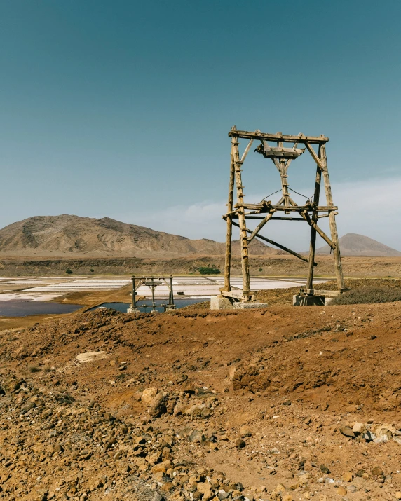 the top of a rusty old style water pump with a large mountain in the background