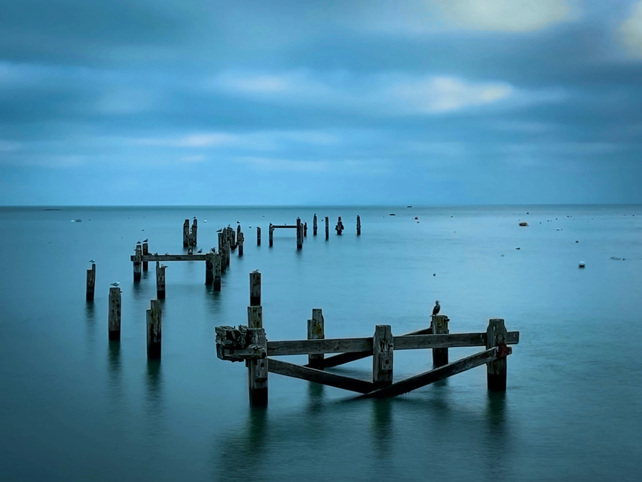 a body of water with a small dock sitting between it and dark clouds