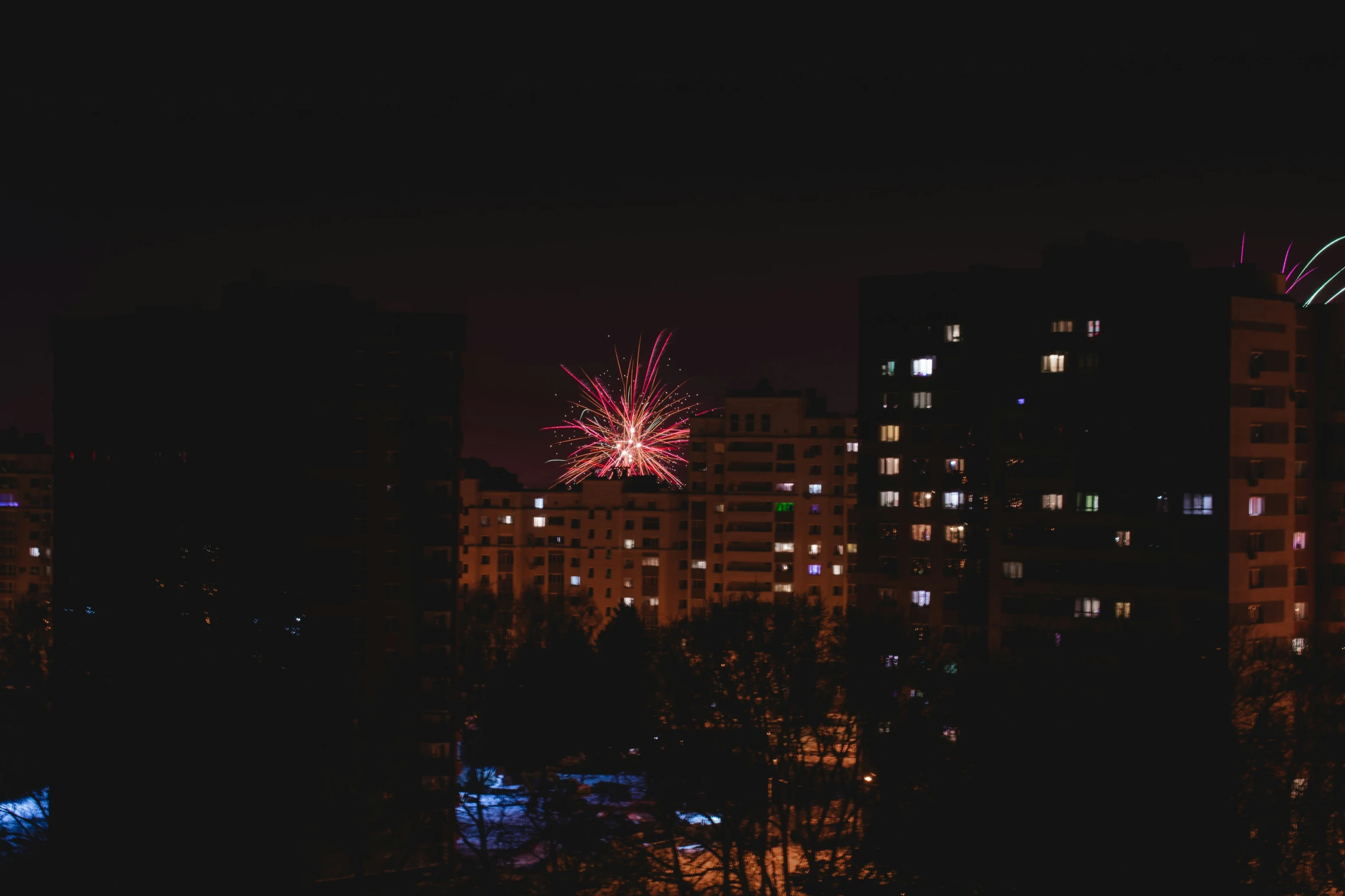 fireworks lit up the sky above some very tall buildings