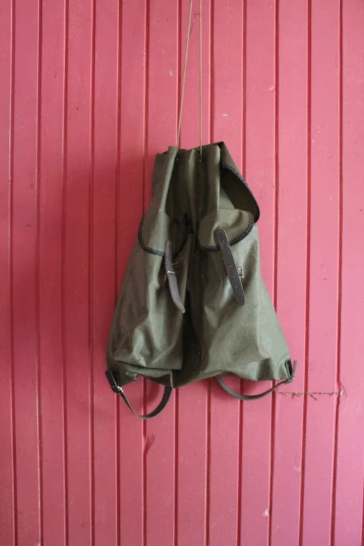 two pouches sitting on the back of a pink wall