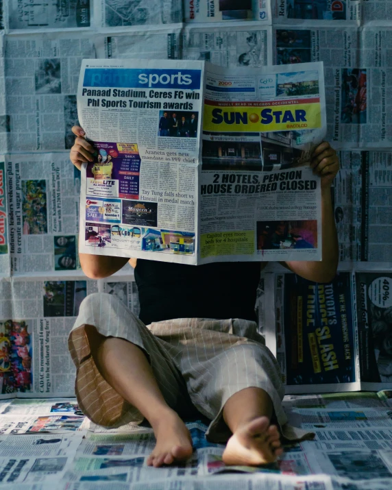 person laying on the floor in front of a newspaper