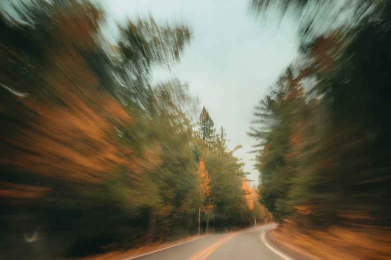 an image of blurry trees and road from car