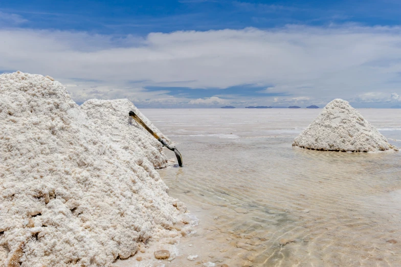 sand mounds with water and clouds in the background