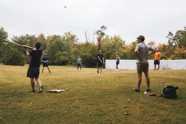 adults playing baseball in backyard area during daytime