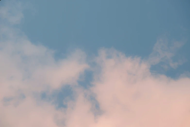 a plane flying in the blue sky near some clouds