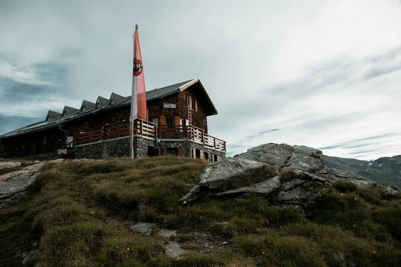 a tall wooden building on the side of a grassy hillside