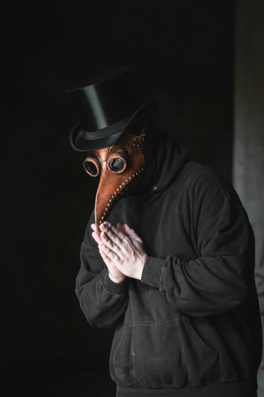 a man wearing a mask and hat holds his hands together