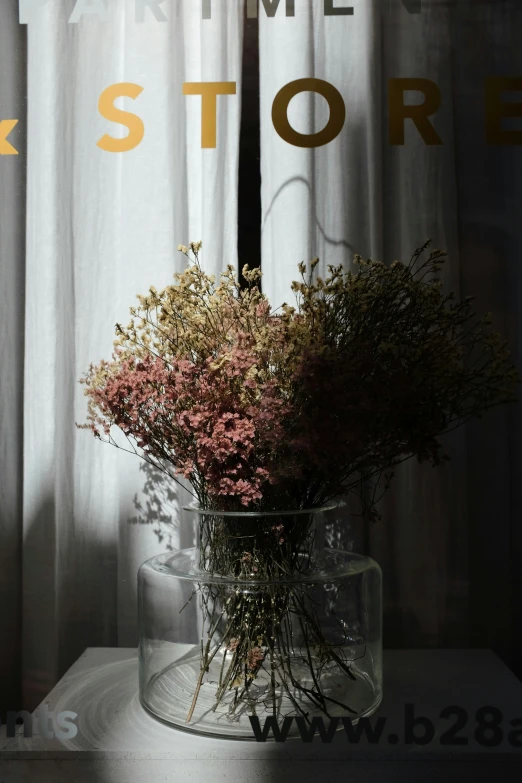 a vase full of dried flowers is sitting near the window