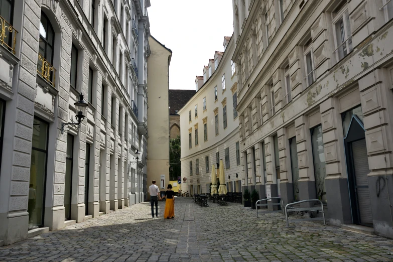 a man and woman are walking down a cobblestone street