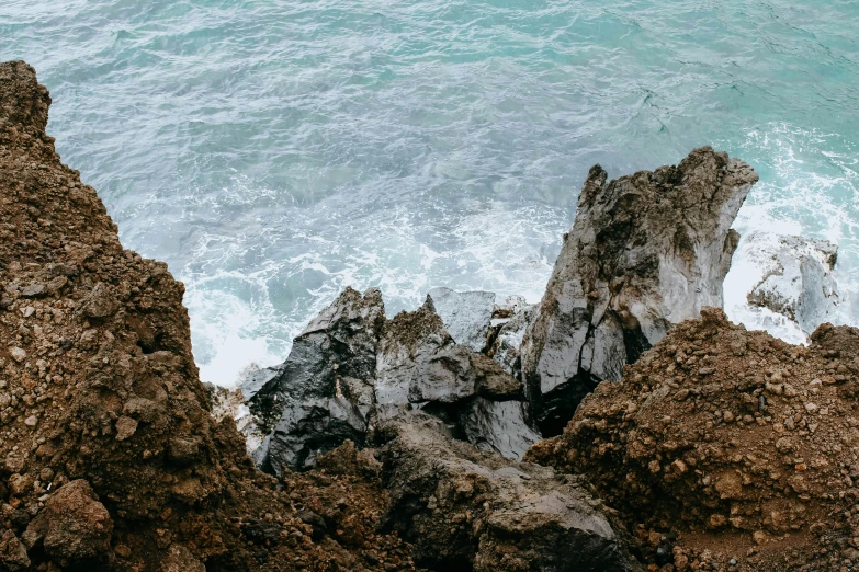 ocean sprays wash across the blue and green water on rocks