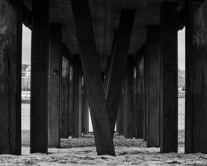 a very tall building with wooden pillars that has some sand underneath it