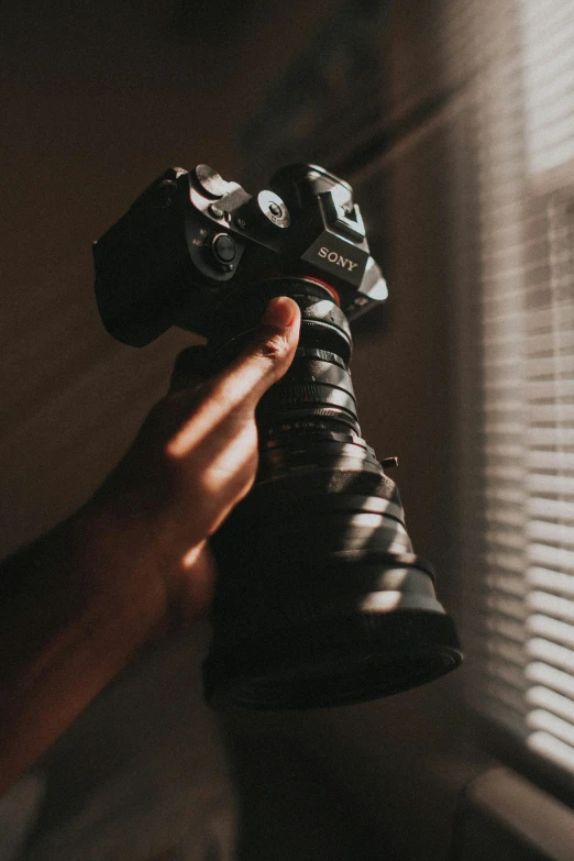 someone holding an old style camera near their window