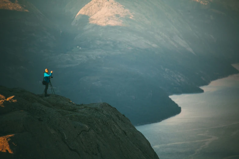 a woman standing on top of a cliff while holding her cell phone