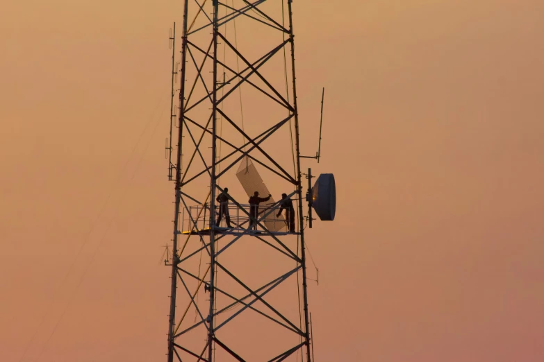 workers are repairing and assembling the antenna tower