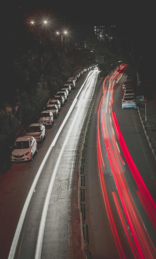 cars are lined up along the highway with street lights at night