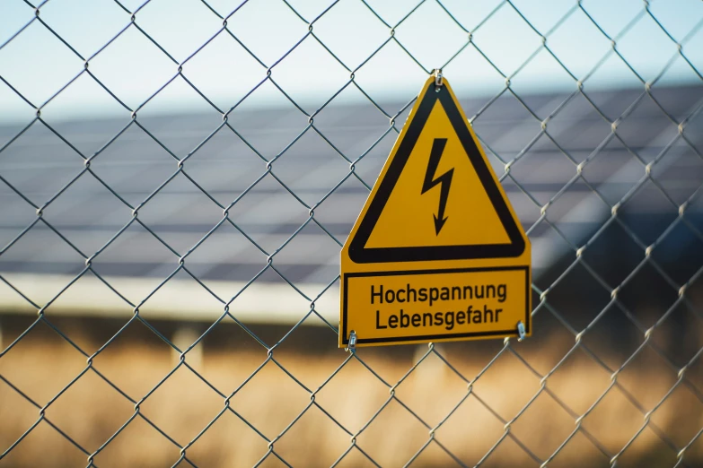 an electrical sign is hanging on a chain link fence