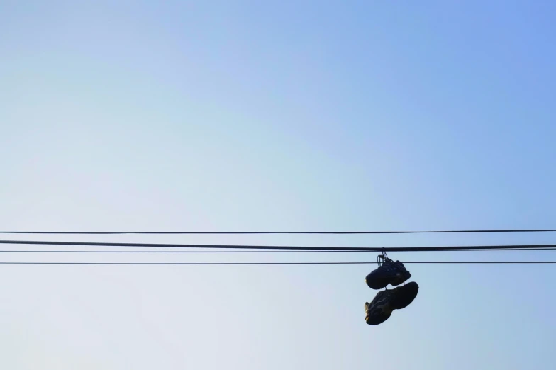 two shoes hanging from wire above clear blue sky