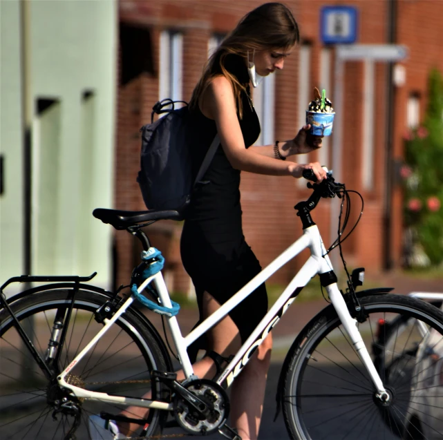 a woman on her bicycle with a cup of coffee