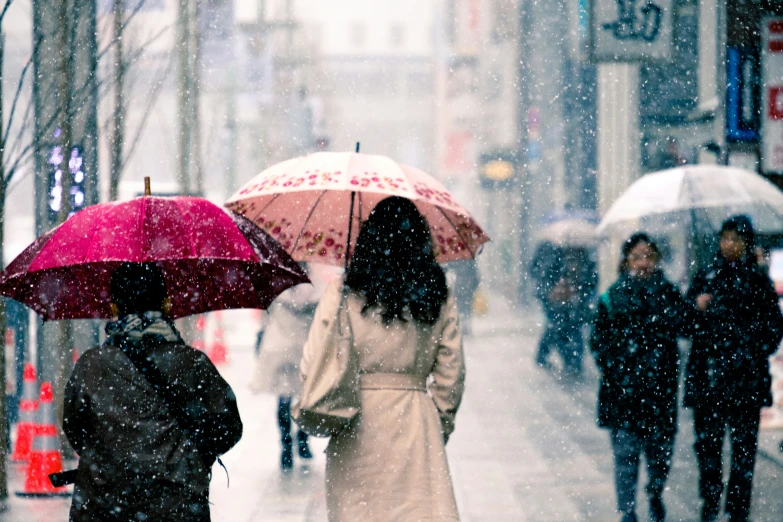 two women with umbrellas standing in the rain on a city street