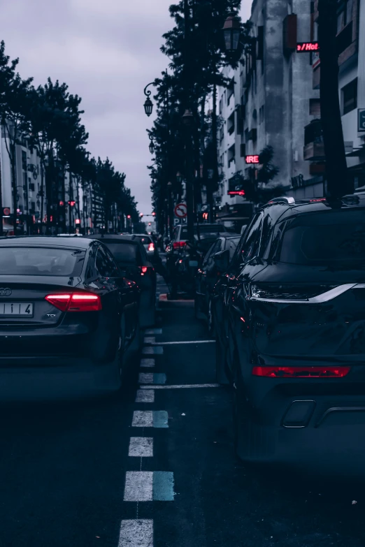 cars drive down the busy city street in dark lighting