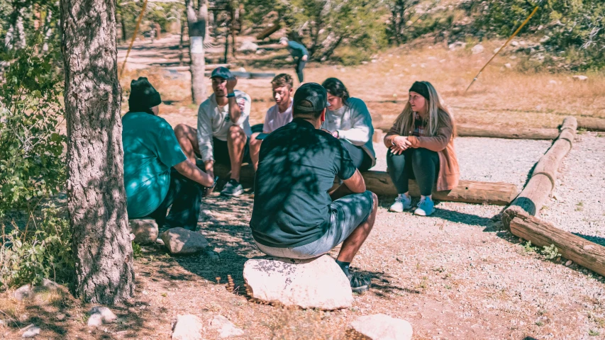 people sit in a circle by some trees