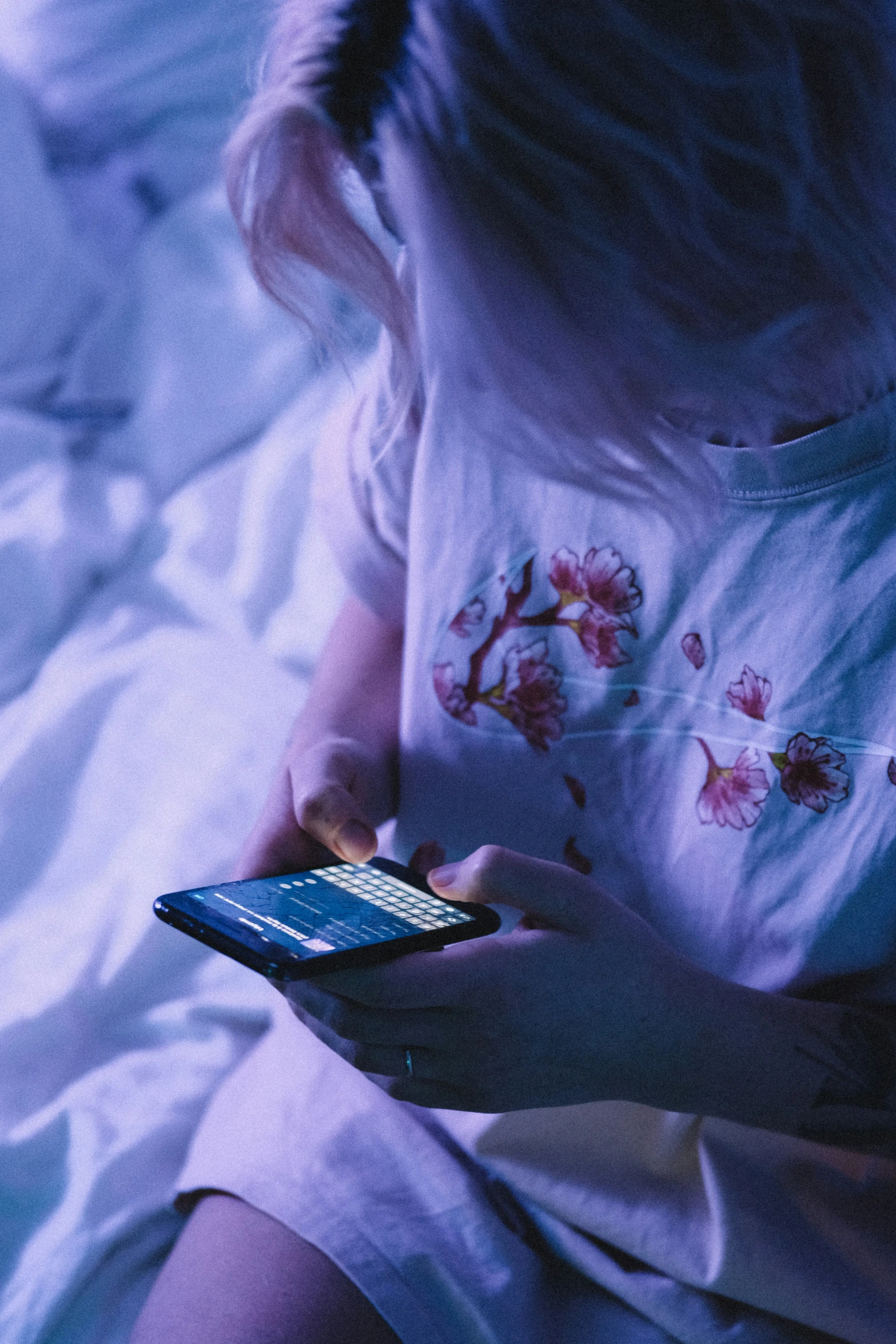 a woman lying in bed looking at a cell phone