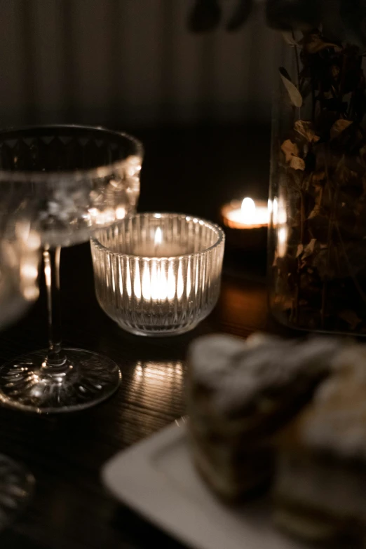 two lit candles and a table with plates of food