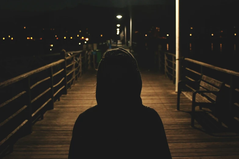 dark night at pier, a man in hooded sweatshirt and street lamp lights