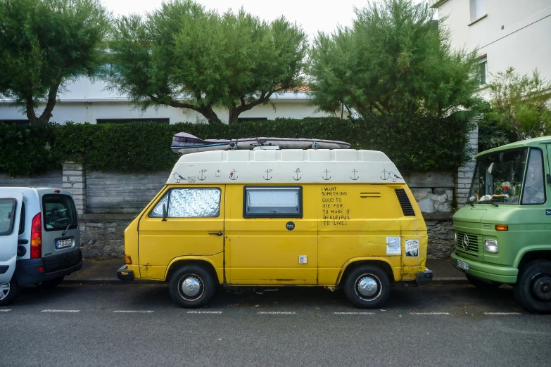 an old yellow van is parked by two other vehicles