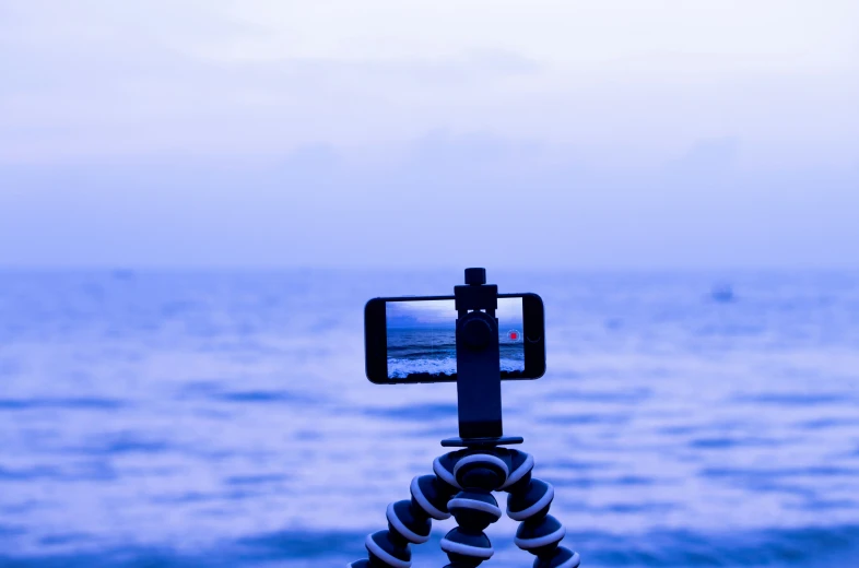 a video camera attached to a tripod taking pos of an ocean