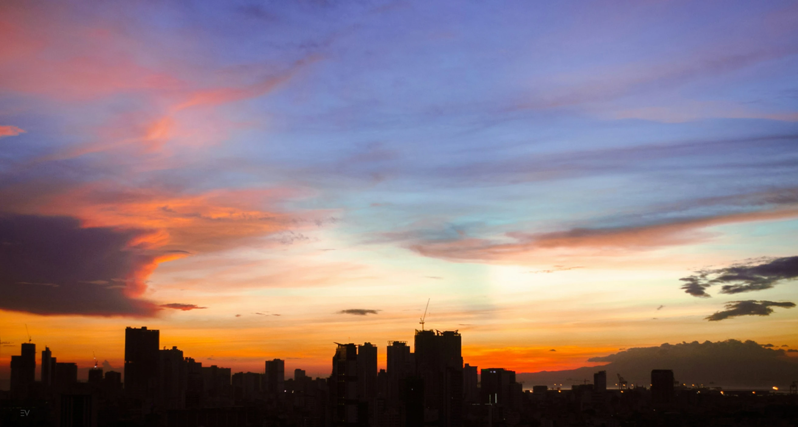 the sun sets in the city behind the skyscrs