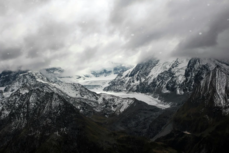 snow - capped mountains under gray skies with a snowy landscape