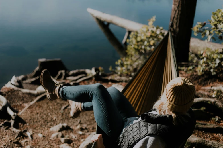 a woman laying in a hammock near a body of water