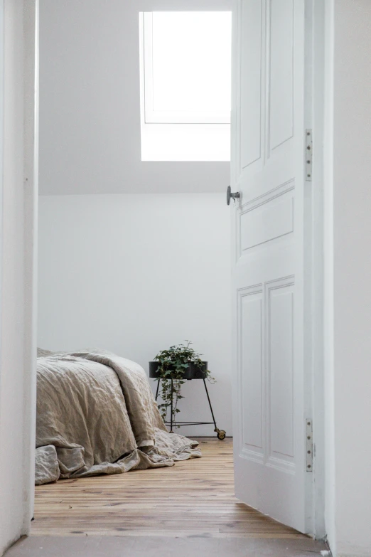 a view from the doorway looking into a bed in a white room