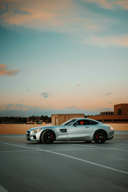 the front end of a silver mercedes car on an empty parking lot